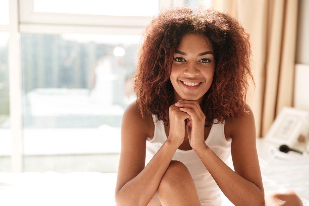 A woman with a bright, relieved smile sitting in a sunlit room