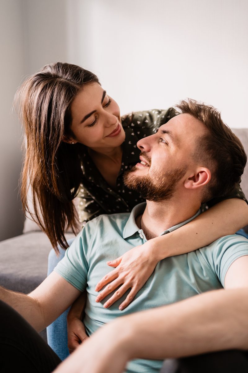 A couple sitting close together on a sofa, smiling at each other