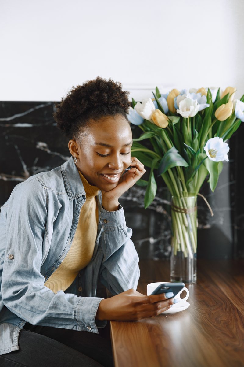 A woman sitting quietly with a cup of coffee and a vase of tulips